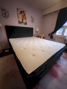 Vihreä samettikankainen sänky sekä sängyn pääty.